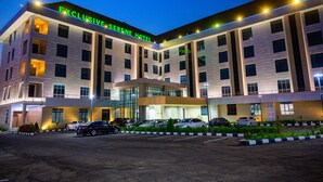 A multi-story hotel with a modern design, featuring a prominent entrance and a parking area with several cars. - Exclusive Serene Hotel Abuja (Abuja)