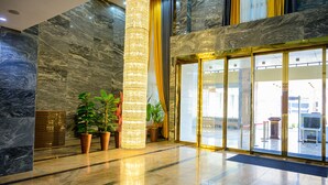 A lobby with marble walls, a large pillar, and potted plants. - Exclusive Serene Hotel Abuja (Abuja)