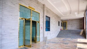 A modern building entrance with a glass door, a sign above the door, and a staircase leading to an upper level. - Exclusive Serene Hotel Abuja (Abuja)