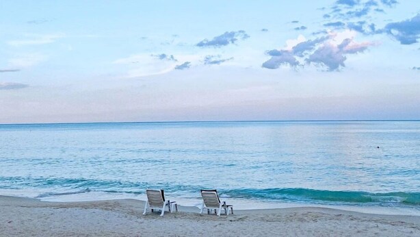 A beach with two lounge chairs facing the ocean. - Fair House Beach Resort & Hotel (Koh Samui)