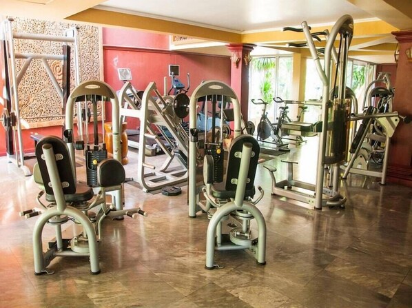 A gym with various exercise machines, including treadmills and weight machines, arranged in a spacious room with a tiled floor. - Fair House Beach Resort & Hotel (Koh Samui)