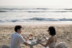 A beachside dining table with food and drinks, overlooking the ocean. - TIA Wellness Resort (Da Nang Municipality)