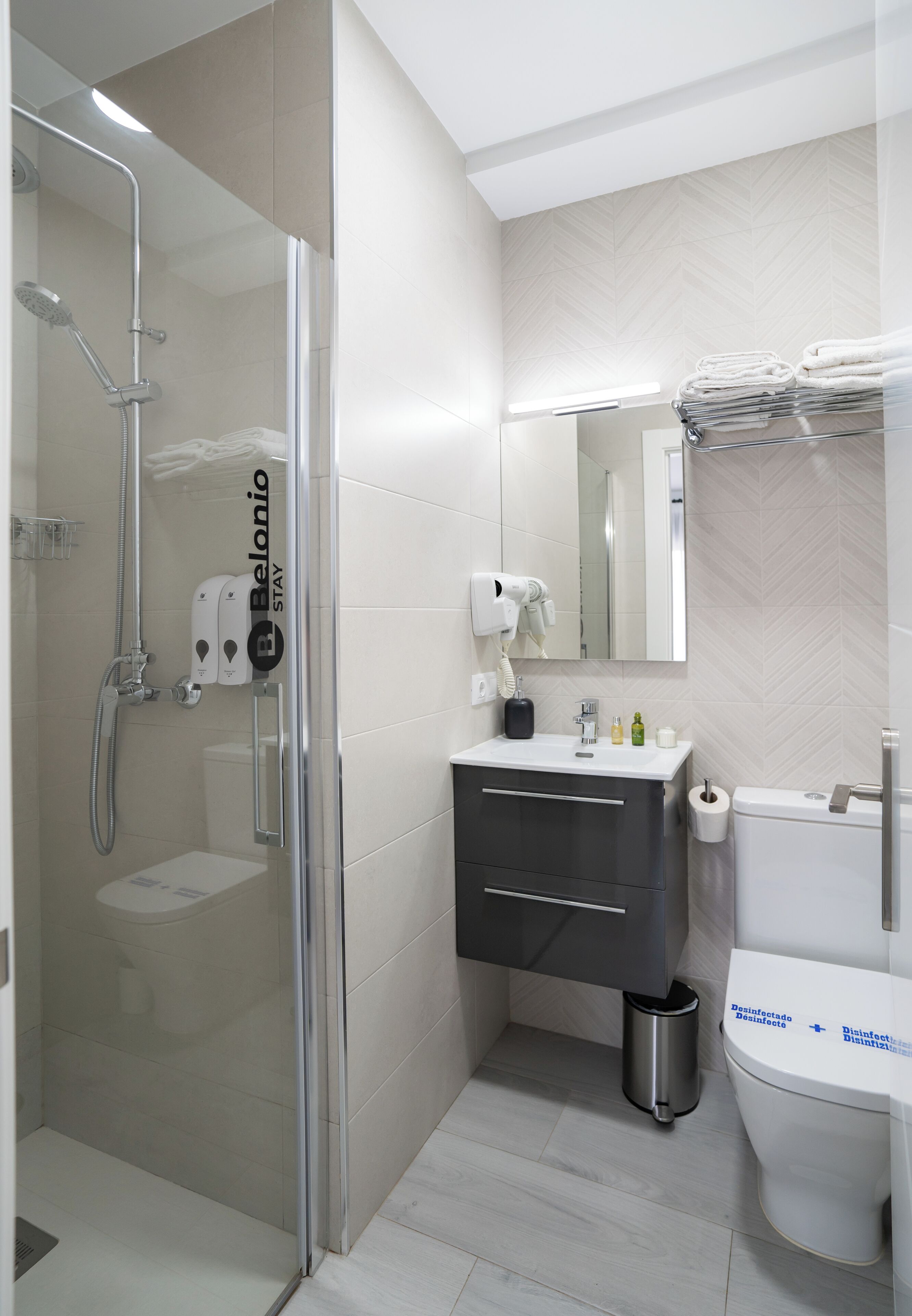 Un baño moderno con ducha de vidrio, tocador con espejo y retrete.