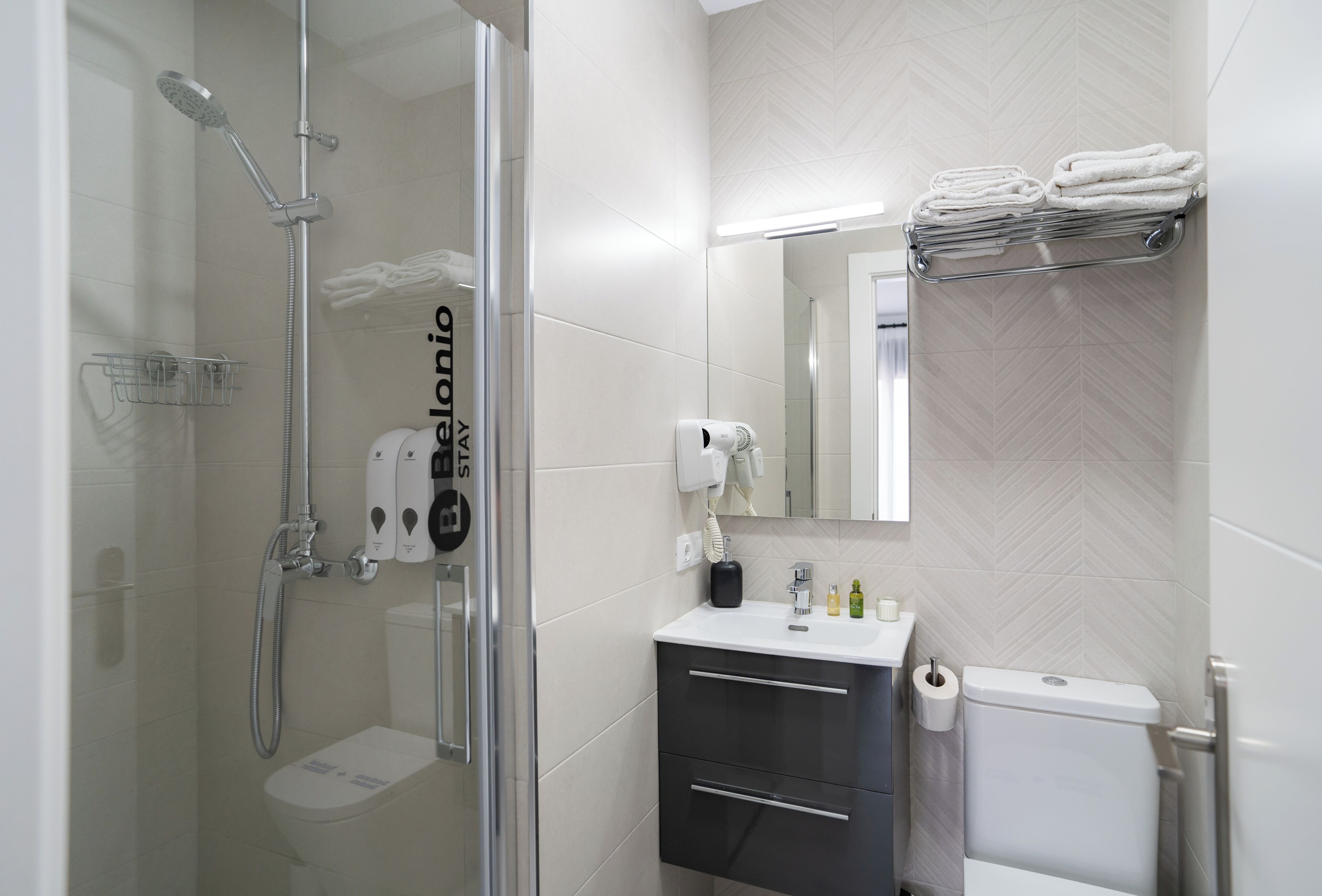 Ein modernes Badezimmer mit einer Duschkabine, einer Toilette, einem Waschbecken mit Spiegel und einem Handtuchhalter.