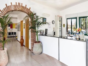 A reception area with a brick archway, potted plants, a desk, and a window with a view.