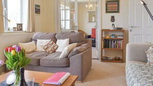 A cozy living room with a grey sofa, a wooden coffee table, and a bookshelf. - Located within a mile of Bideford Quay and 4 miles from Westward Ho. (Bideford)