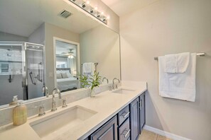 Un baño moderno con un espejo grande, dos lavamanos y un perchero para toallas.