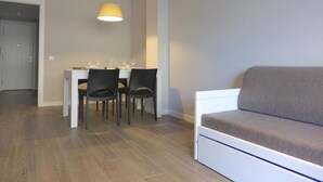 Ein modernes Wohnzimmer mit einer Couch, einem Esstisch mit Stühlen und einer Pendelleuchte.