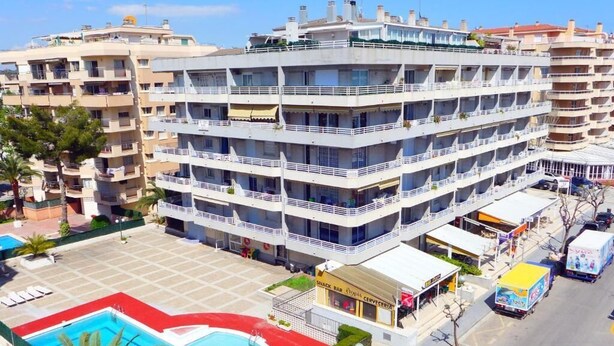 Ein mehrstöckiges Hotel mit Balkonen, einem Poolbereich und einer Snackbar.