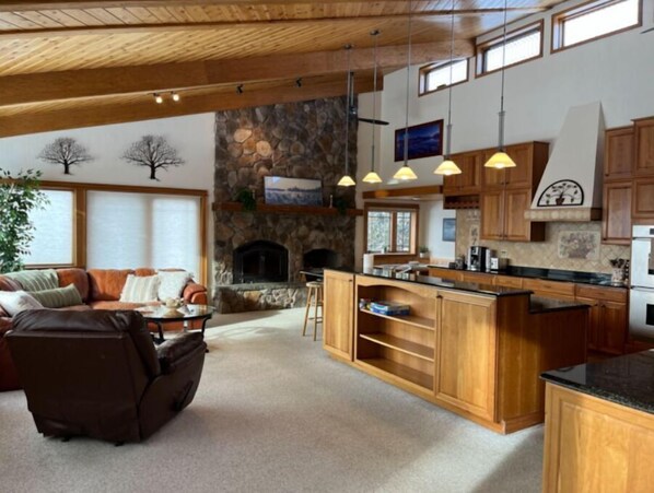 Relax in a spacious living area with a comfortable sofa, stone fireplace, and high ceiling with large windows.