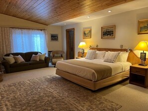 Cozy retreat with a large bed, nightstands, and a sofa, set against a backdrop of framed artwork and a patterned rug.