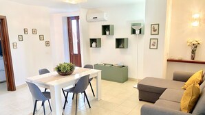 Un salon moderne avec une table à manger, un canapé gris et un mur d’accent vert.