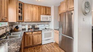 A kitchen with wooden cabinets, a stainless steel refrigerator, a microwave, and a stove. - Centrally located for adventures (Westminster)