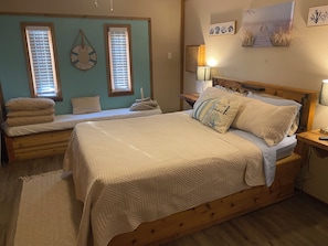 Relax in this serene bedroom with a large bed, quilted headboard, and matching quilt.