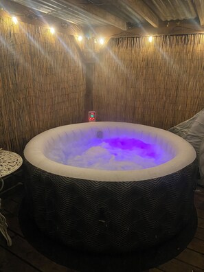 Relax in a tranquil space with a central hot tub, bamboo wall design, and ambient lighting.
