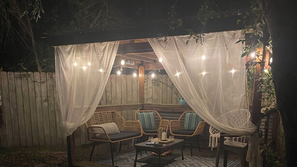 Une terrasse extérieure dotée d’un auvent, de chaises en osier et d’une table.