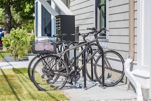 Una bicicleta estacionada en la acera frente a un edificio de fachada blanca y un buzón negro.
