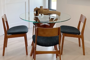 Una mesa redonda de vidrio con un centro de madera, rodeada por cuatro sillas de madera con asientos acolchados.