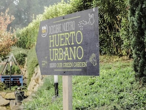 A sign with text 'DESCUBRE NUESTRA HUERTO URBANO DISCOVER OUR GREEN GARDEN' and a logo 'ACTING HERE Planet 21'. - Ibis Girona Costa Brava (Girona)