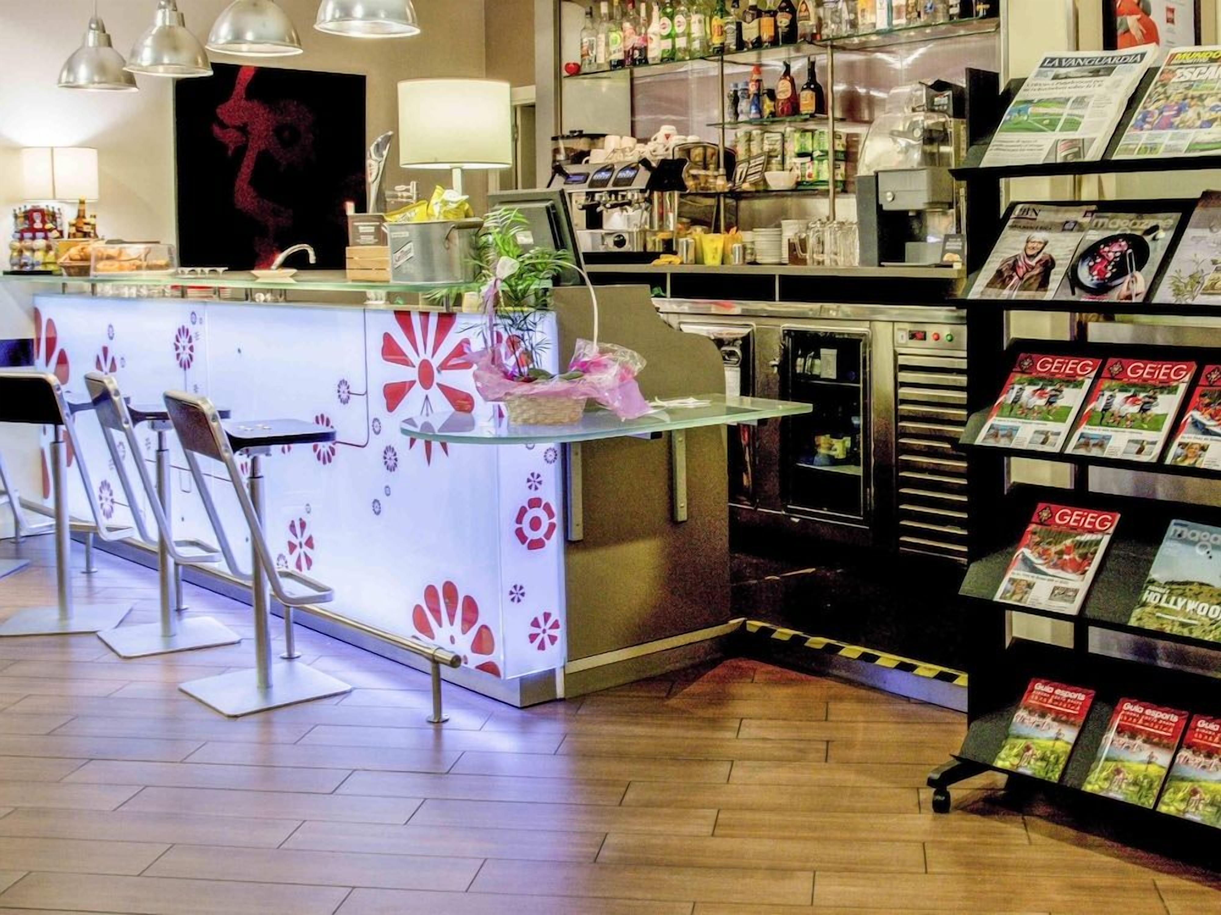 Zona de bar con mostrador, sillas y una exhibición de revistas.