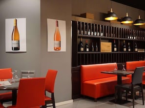 A restaurant interior with red seating, a wine rack, and pendant lighting. - Ibis Girona Costa Brava (Girona)