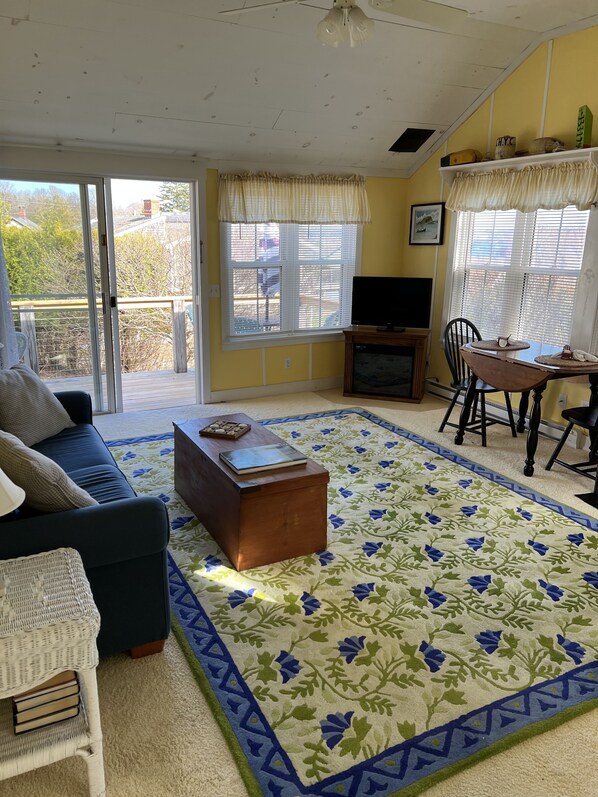 A living room with a sofa, a coffee table, a TV, and a dining area with chairs and a table.