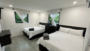 A hotel room with two beds, a desk, and a window with curtains.