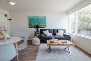 Una sala de estar moderna con un sofá gris, una mesa de centro redonda y un ventanal grande.