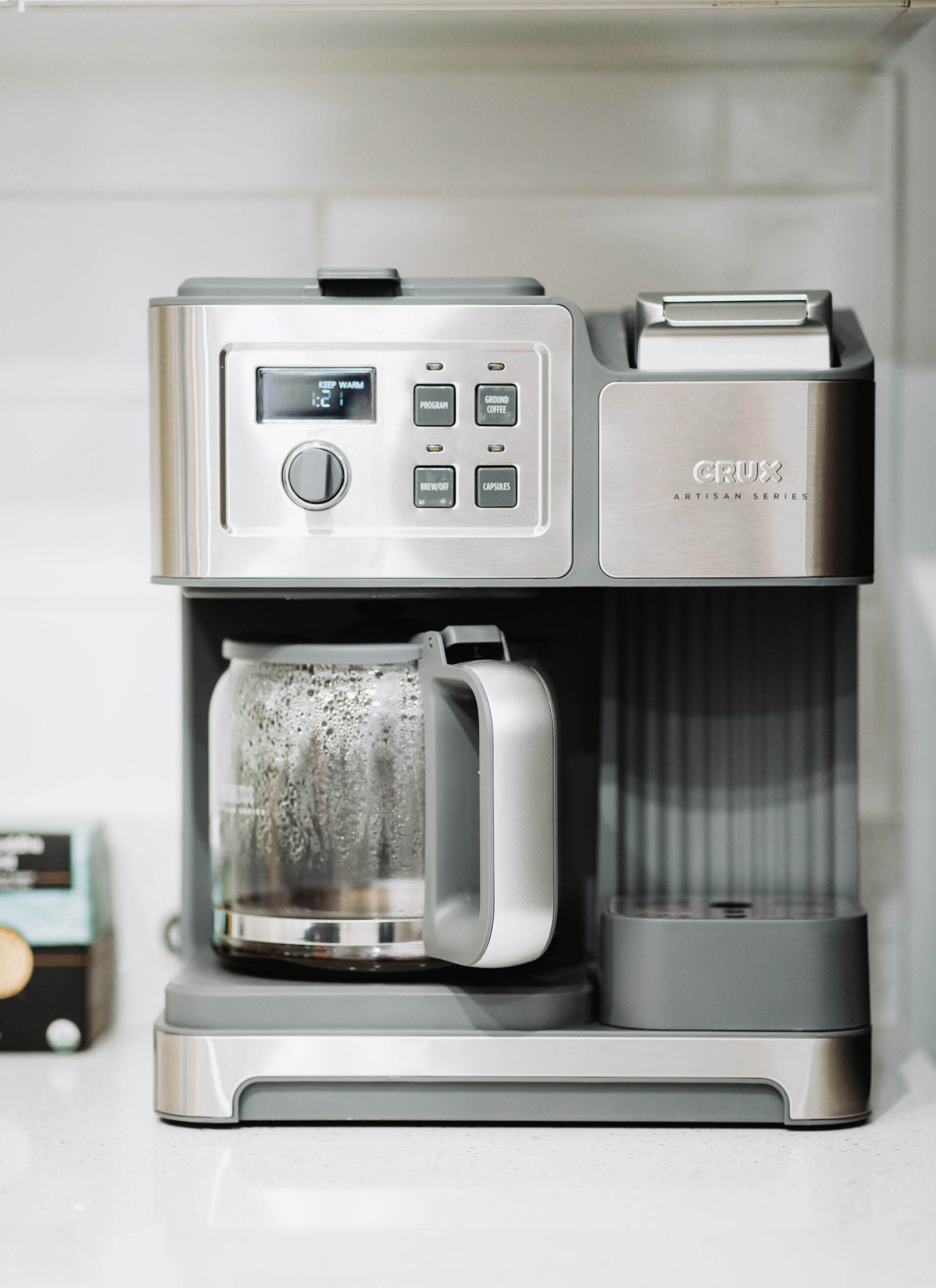 Eine Kaffeemaschine mit digitaler Anzeige und mehreren Tasten, darunter Optionen für Programmierung, gemahlenen Kaffee, Ausschalten und Kapseln.