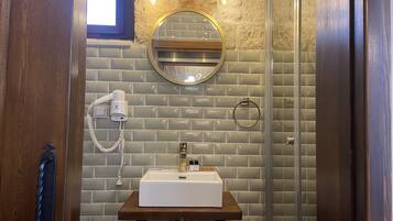 A bathroom with a wooden vanity, a round mirror, a towel ring, and a hairdryer on the wall.