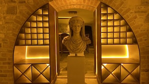 A marble bust in a warmly lit alcove with stone walls and wooden shelving. - Dionysos 1789 Boutique Hotel (Foça)
