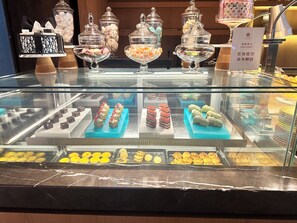 Ett vitrinskåp med ett urval av bakverk och desserter, inklusive tårtor och kakor, som är arrangerade på blå brickor.