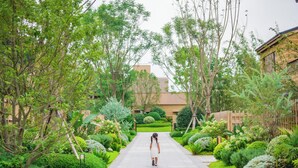 A pathway lined with lush greenery and a building in the background. - Angsana Chengdu Wenjiang (Chengdu)