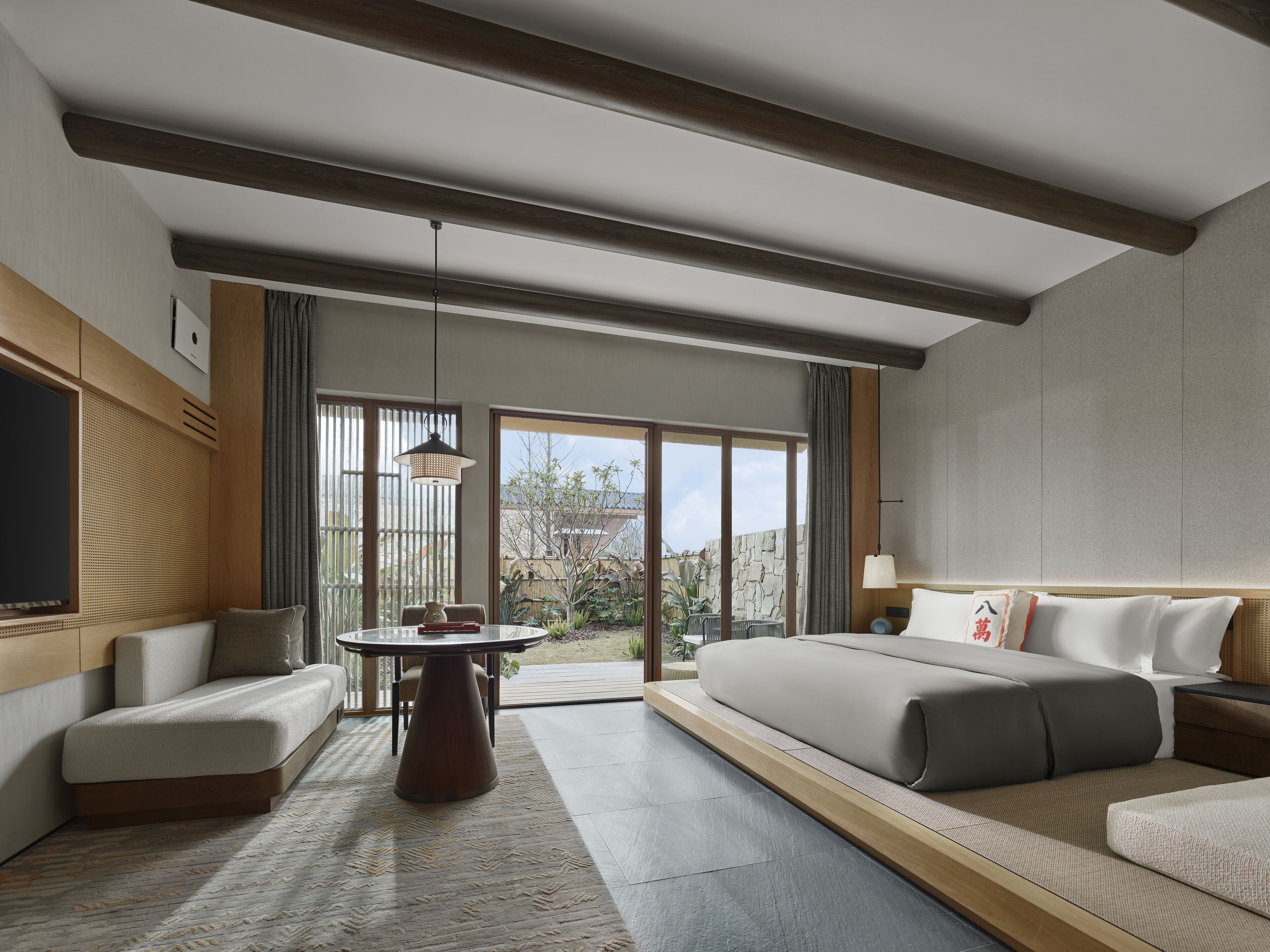Habitación de hotel moderna con una cama grande, un sofá, una mesa de comedor y vistas al exterior.