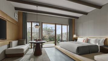 Habitación de hotel moderna con una cama grande, un sofá, una mesa de comedor y vistas al exterior.