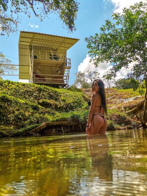 A woman in a bikini standing in a natural pool with a building in the background. - Paraiso Escondido Cabañas  (San Luis)