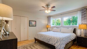A bedroom with a bed, bedside lamps, a ceiling fan, a window with curtains, and a rug. - Greenbelt Access & Views, Close to DT (Austin)