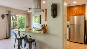 A modern kitchen with a central island, bar stools, a stainless steel refrigerator, and wooden cabinets. - Greenbelt Access & Views, Close to DT (Austin)