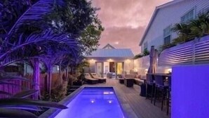 A pool area with a wooden deck, lounge chairs, and a covered seating area. - THE CLASSY CONCH- Old Town Key West (Key West)