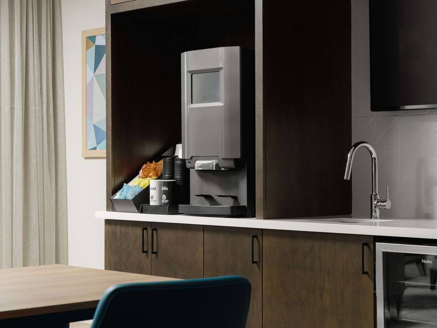 A modern kitchen with a coffee machine, a sink, and a refrigerator.