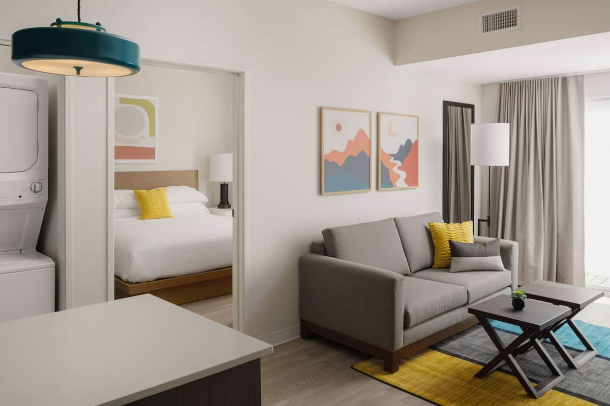 Una habitación de hotel moderna con cama, sofá y una pequeña mesa.