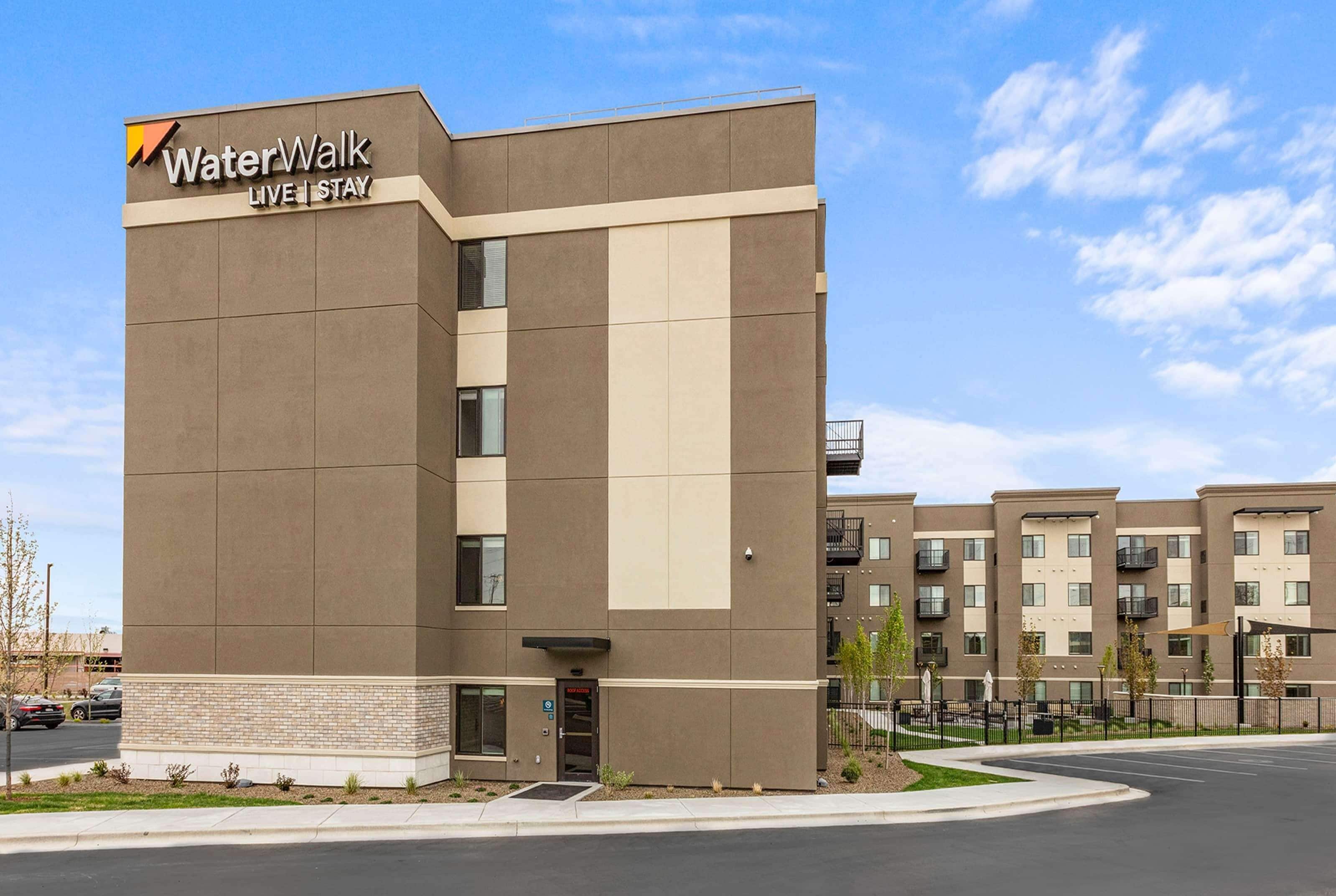 A modern hotel building with a sign reading "WaterWalk Live Stay."