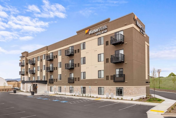 A WaterWalk hotel with a modern design, featuring multiple balconies and a parking lot in front.