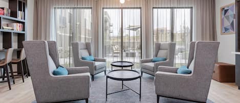 A modern living room with grey armchairs, a coffee table, and a bookshelf.