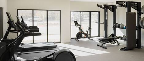 A gym with treadmills, an elliptical, a stationary bike, a bench, dumbbells, and a weight machine.