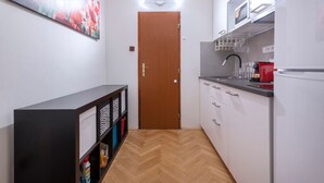 Une cuisine étroite avec des meubles blancs, une porte en bois et un parquet en chevrons.