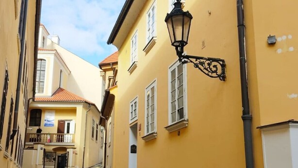 Une rue étroite bordée d’immeubles jaunes, un chemin pavé et un lampadaire noir.
