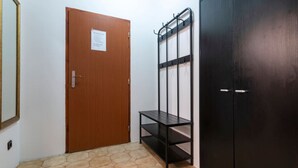 Une pièce avec une porte en bois, une étagère en métal noir et une armoire noire.