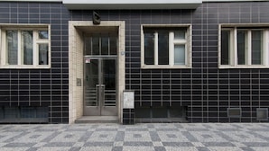 A building facade with a tiled entrance, two windows, and a door with a glass panel. - Quiet Studio by Anděl Metro - Walk to Old Town, Next to Nový Smíchov Mall (Prague)