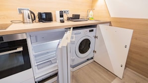 A compact kitchen with a built-in washing machine, a coffee maker, and a microwave. - Quiet Studio by Anděl Metro - Walk to Old Town, Next to Nový Smíchov Mall (Prague)